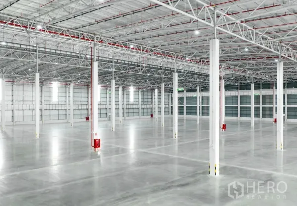 Warehouse for rent in Si Racha, Chon Buri - Wide warehouse hall with polished concrete floor, rows of columns, and overhead lighting with fire piping.