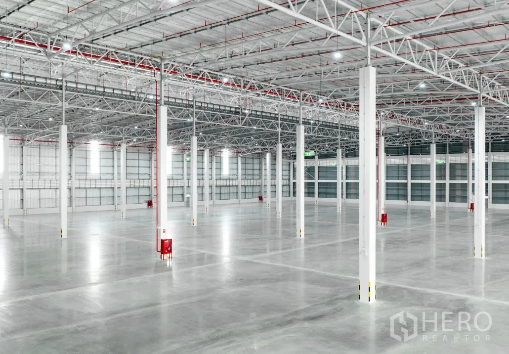 Warehouse for rent in Si Racha, Chon Buri - Wide warehouse hall with polished concrete floor, rows of columns, and overhead lighting with fire piping.