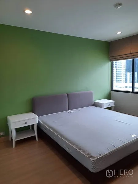 Condominium for rent in Watthana, Bangkok - Second bedroom featuring a green accent wall, double bed, city-facing window and nightstands.