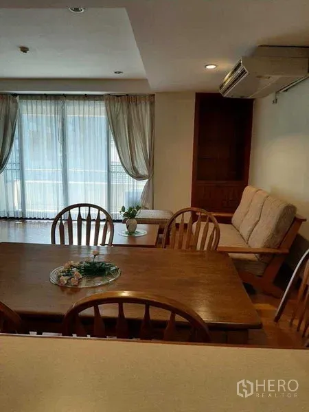 Apartment for rent in Watthana, Bangkok - Sunlit living and dining area with wooden floors, balcony and sheer curtains.