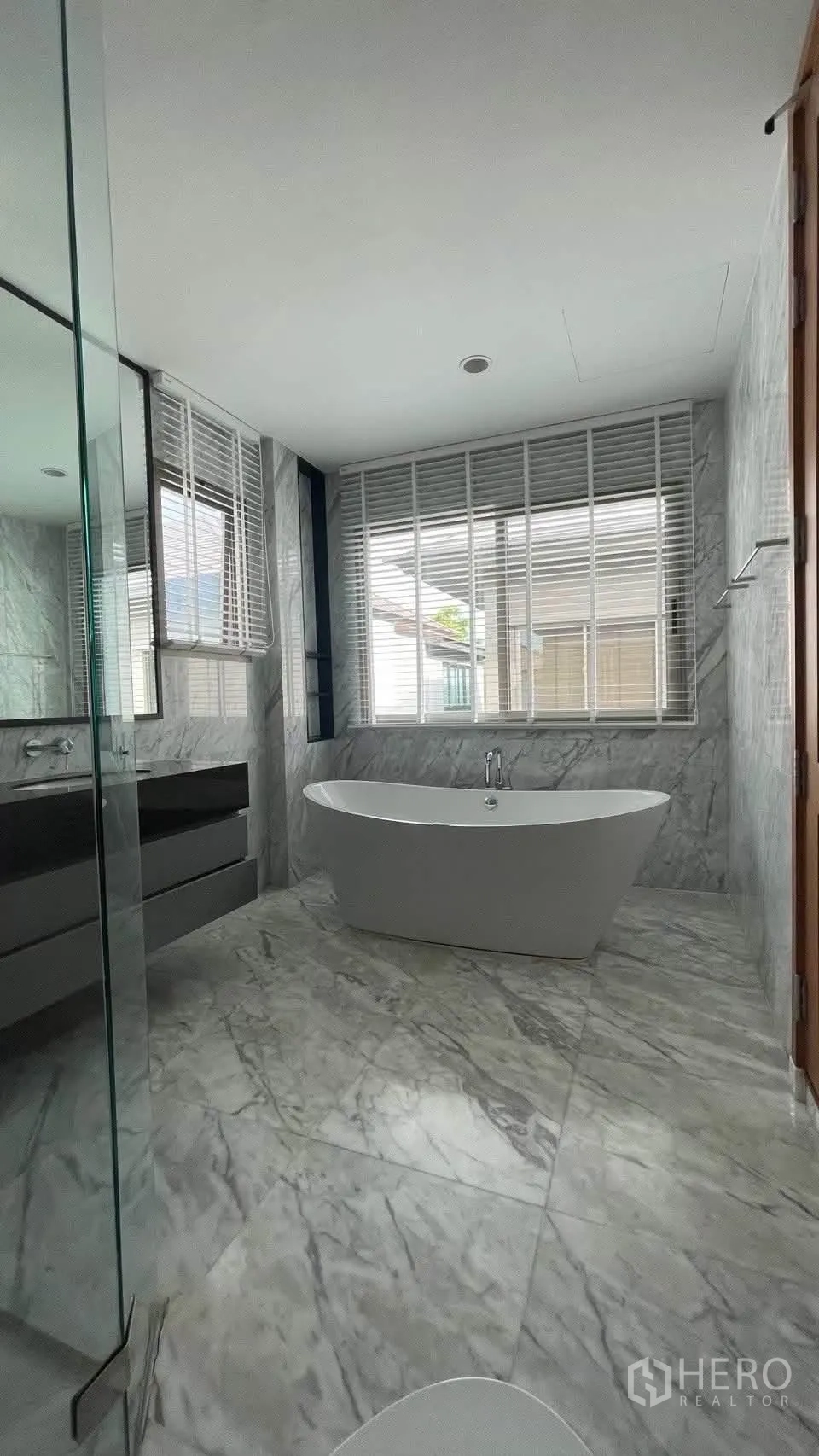 Detached House for rent in Prawet, Bangkok - Marble bathroom with freestanding bathtub, glass shower and wide windows.