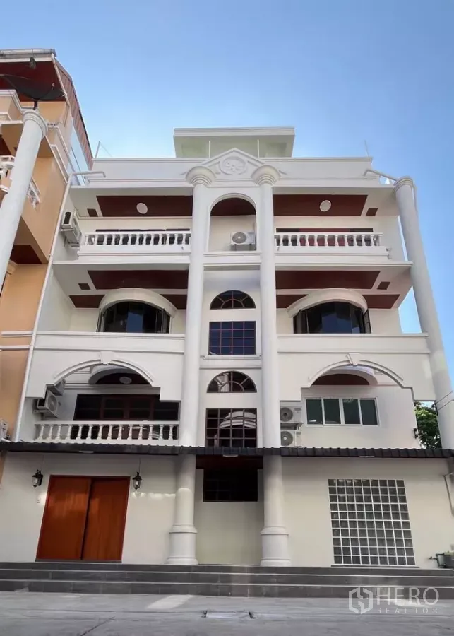 带办公室的家 出租在Watthana, Bangkok - 瓦塔纳五层家办外立面，经典与现代并存的立柱与阳台，在蓝天下。
