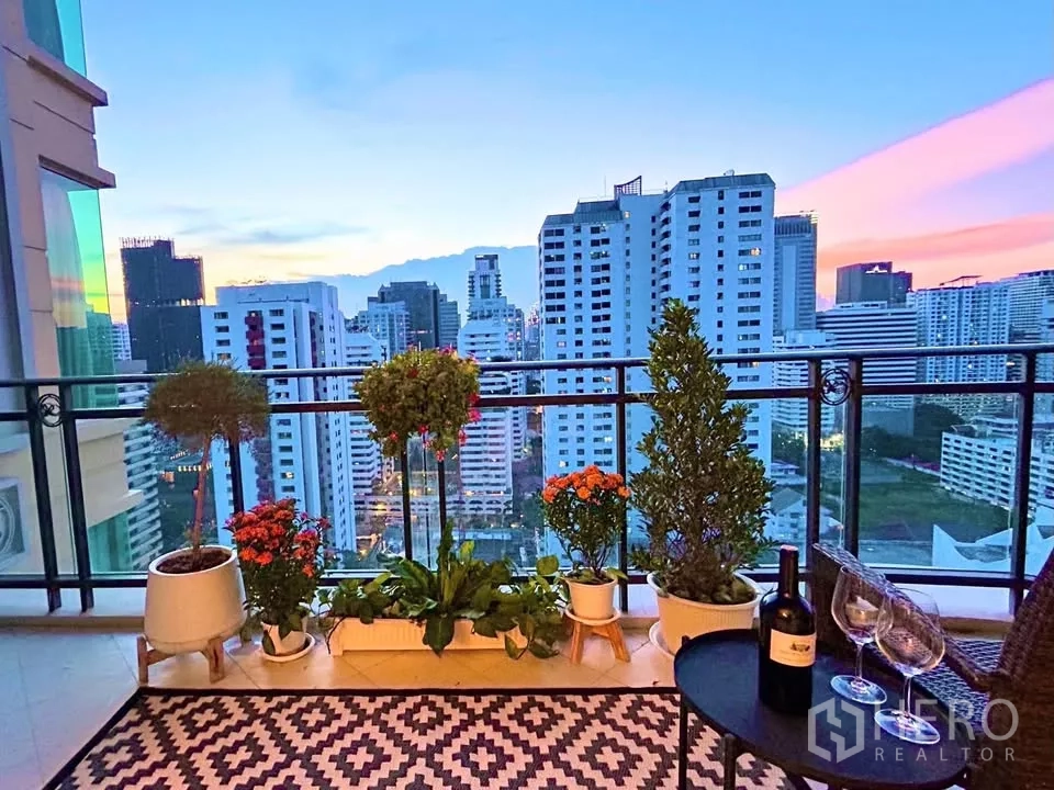 Condominium for sale in Watthana, Bangkok - Evening skyline from the balcony with plants and a small table set with wine glasses.