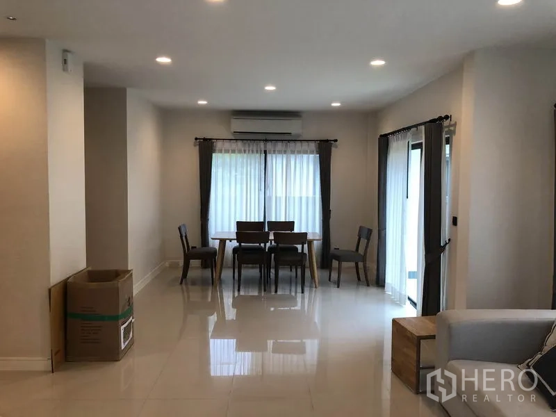 Detached House for rent in Bang Kapi, Bangkok - Dining area with wooden table and chairs, sheer curtains and glossy tile floors.