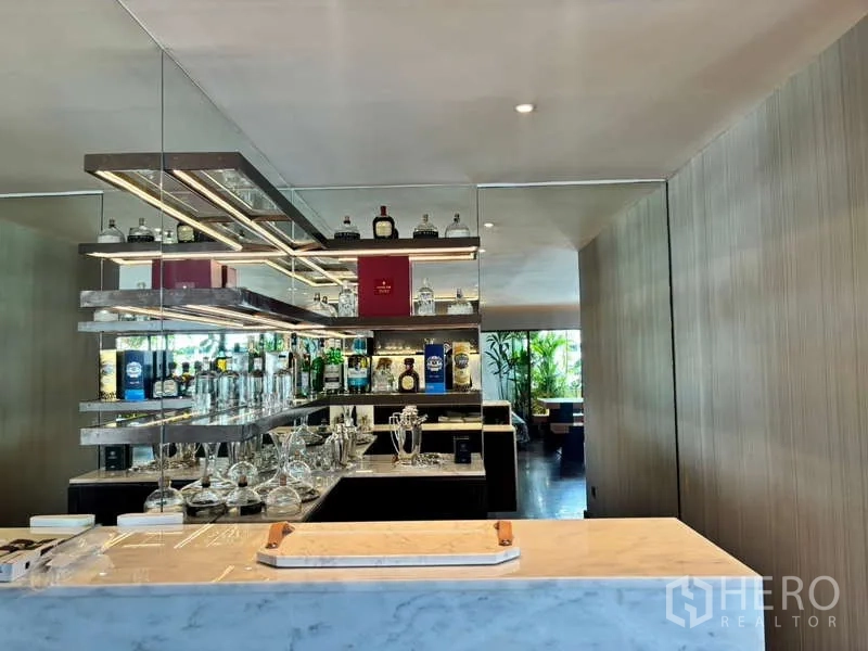 Condominium for rent in Watthana, Bangkok - Mirrored home bar with illuminated shelving, bottles and glassware.
