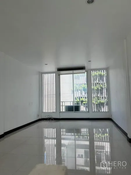店屋 出租在Khlong Toei, Bangkok - 楼上采光明亮的房间，白色地砖，高窗，并有滑门通向小阳台