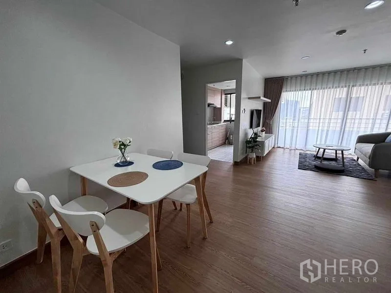Shophouse for rent in Watthana, Bangkok - Dining nook with a white table and chairs beside the doorway to a separate kitchen.