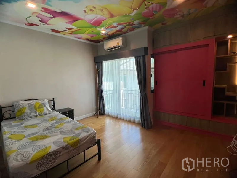 Detached House for rent or sale in Prawet, Bangkok - Children’s bedroom with colorful ceiling mural, balcony doors and a built-in closet.