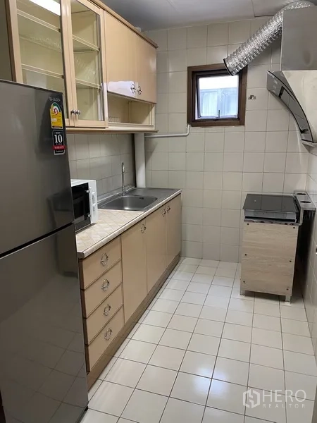 Condominium for rent or sale in Watthana, Bangkok - Separate kitchen with cabinetry, refrigerator, sink and microwave.