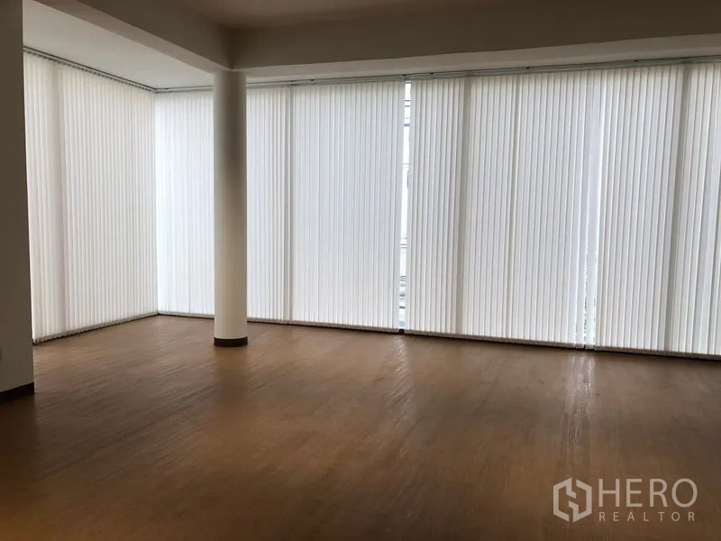 Office Space for rent in Bang Rak, Bangkok - Corner open-plan room with floor-to-ceiling vertical blinds and wood flooring.