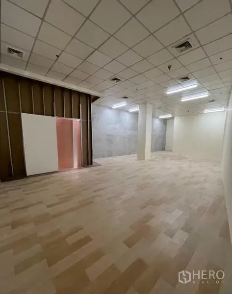 Retail Space for rent in Watthana, Bangkok - Wide shop interior with grid ceiling, LED strip lights and a panelled partition at the entrance.