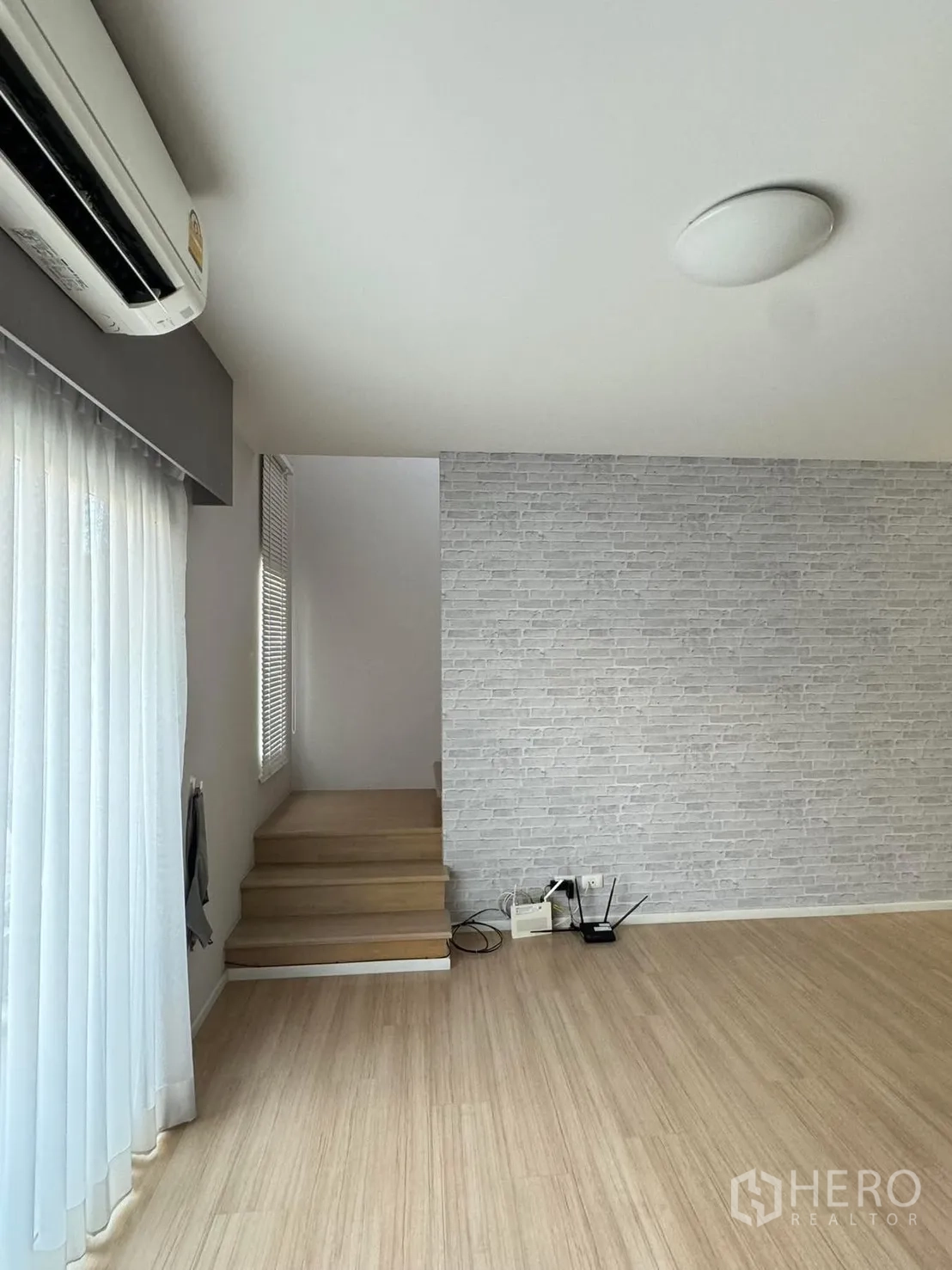 Townhouse for rent in Suan Luang, Bangkok - Bright landing with white brick feature wall, short steps and sheer curtains.