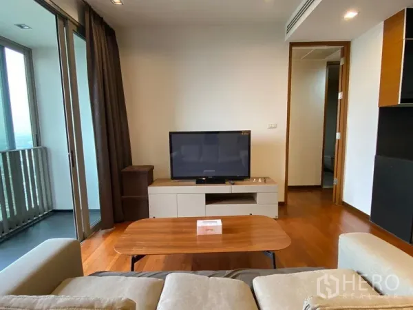Condominium for rent - Cozy lounge with TV unit and coffee table, sliding doors to a covered balcony and hallway to bedrooms.