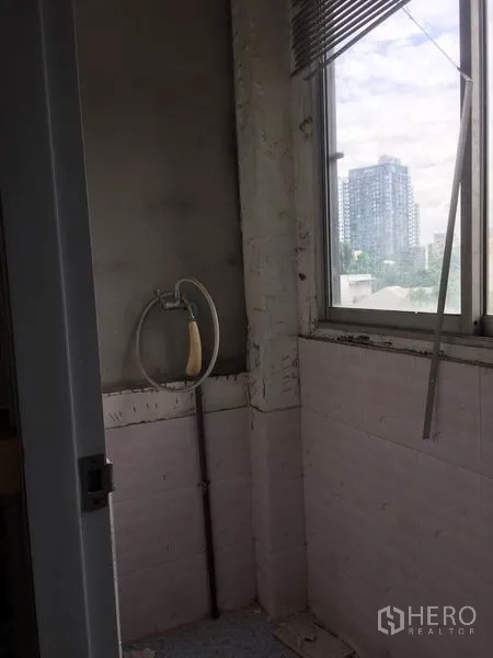 Shophouse for rent in Khlong Toei, Bangkok - Bathroom corner with handheld shower and a city view through the window.