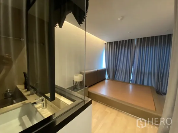 Condominium for rent in Bang Rak, Bangkok - Bedroom with platform bed and glass partition overlooking the ensuite bathroom in a Bang Rak condominium.