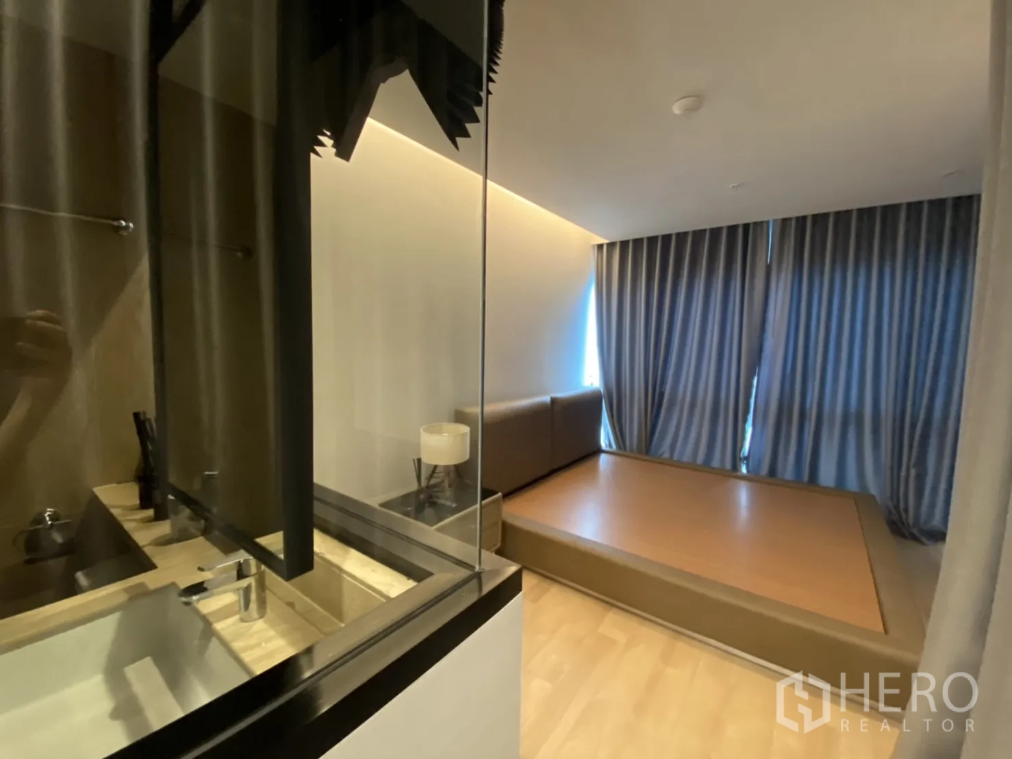 Condominium for rent in Bang Rak, Bangkok - Bedroom with platform bed and glass partition overlooking the ensuite bathroom in a Bang Rak condominium.