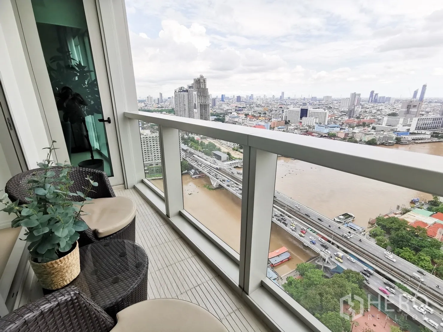 คอนโด ให้เช่าหรือขายในKhlong San, Bangkok - ระเบียงชั้นสูงพร้อมชุดหวายและวิวแม่น้ำเจ้าพระยาพาโนรามา