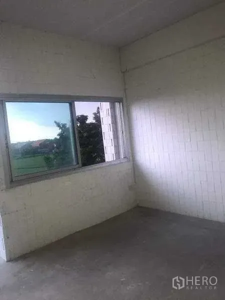 货栈 出租在Pathum Thani - 带推拉窗的角落房间，白色砖墙，窗外可见绿色景观