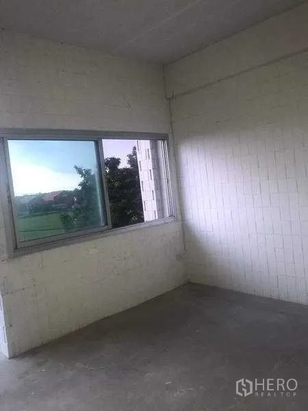 货栈 出租在Pathum Thani - 带推拉窗的角落房间，白色砖墙，窗外可见绿色景观