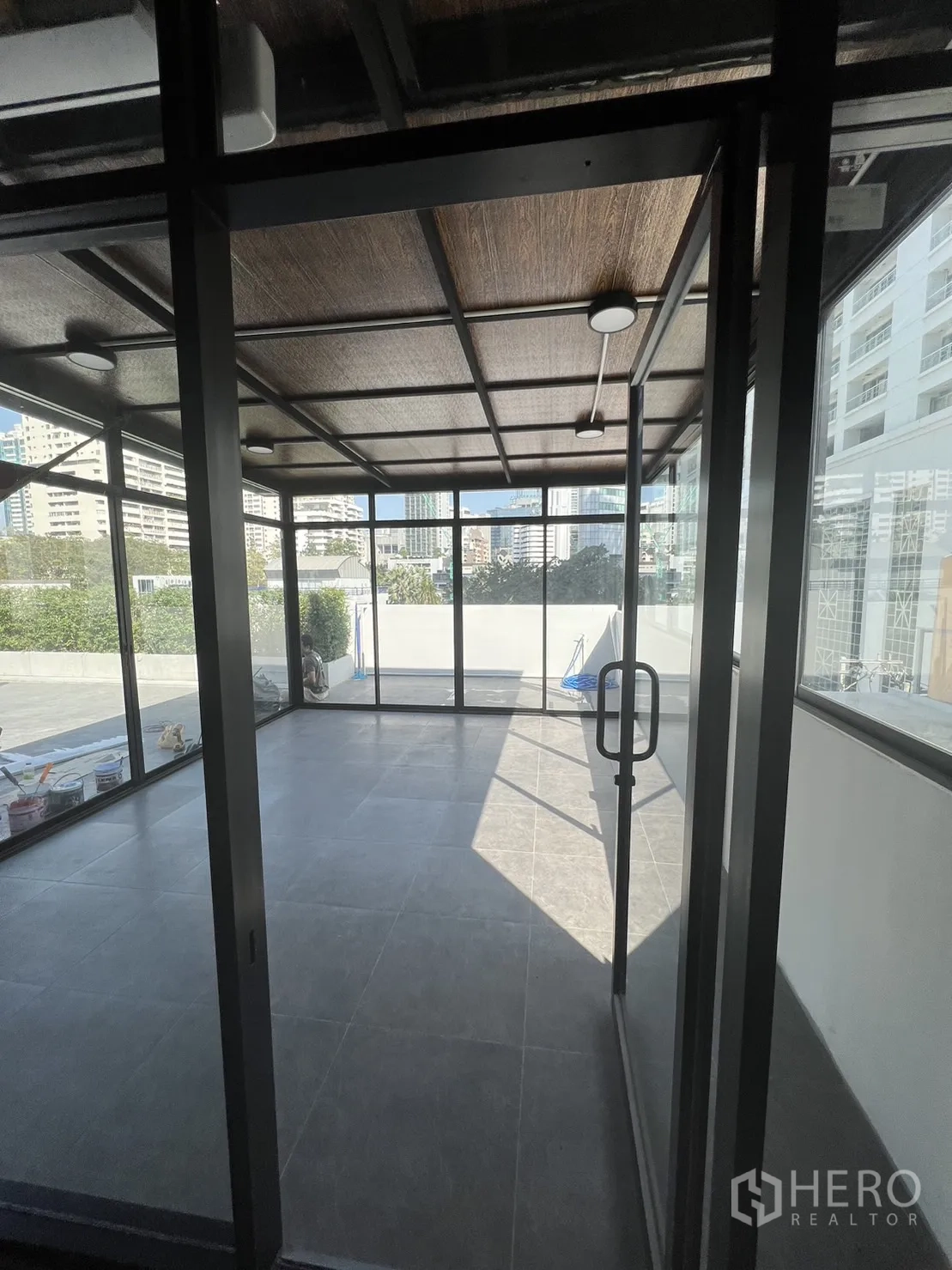 Retail Space for rent in Watthana, Bangkok - Bright glass-walled retail unit with gray tile floors and wood-look ceiling opening to a terrace.