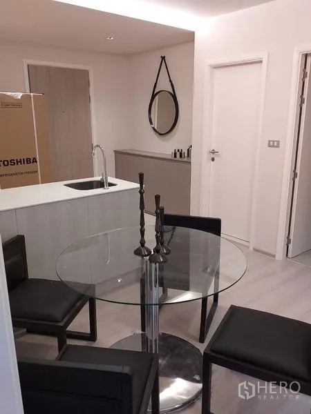 Condominium for rent in Khlong Toei, Bangkok - Compact kitchen island with sink facing a round dining set and the entry door in a contemporary condo.