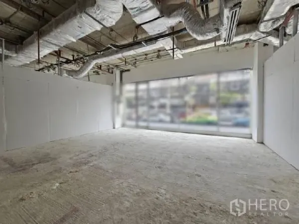 Retail Space for rent - Open-plan shop unit with white partition walls, full-width windows and exposed ceiling services.
