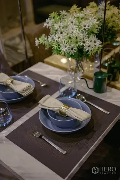 Condominium for rent in Watthana, Bangkok - Close-up of table setting with bowls, napkins and a vase of white daisies.
