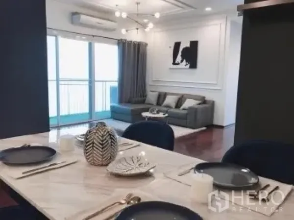 公寓 出售在Watthana, Bangkok - 餐区大理石桌，面向客厅与阳台，配现代吊灯。