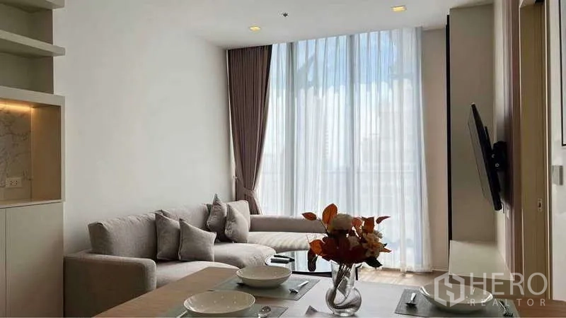 公寓 出租在Watthana, Bangkok - 开放式客餐厅，大幅窗户与浅色系装潢，透过纱帘可见城市景观。