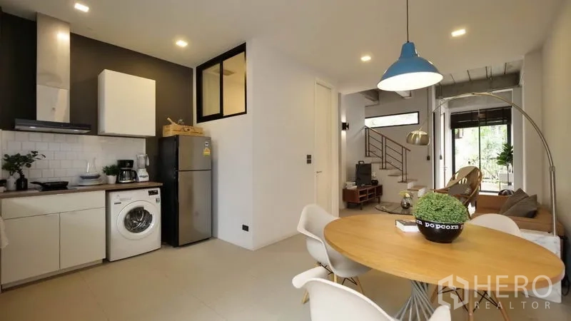 Townhouse for rent in Huai Khwang, Bangkok - Open-plan kitchen and dining area with round table, pendant light and view to the living room.