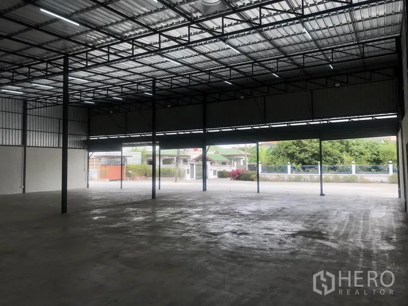 Warehouse for rent in Pathum Thani - Open-span warehouse with large entrance, ample driveway, and view of the surrounding neighborhood in Pathum Thani.