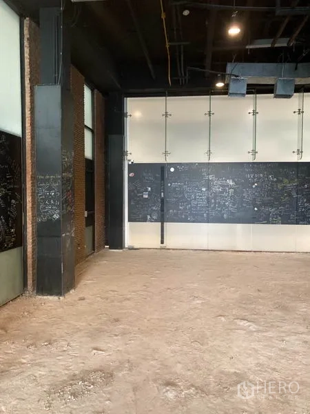 Retail Space for rent in Watthana, Bangkok - Spacious shop interior with unfinished floor, black feature wall and brick accents.