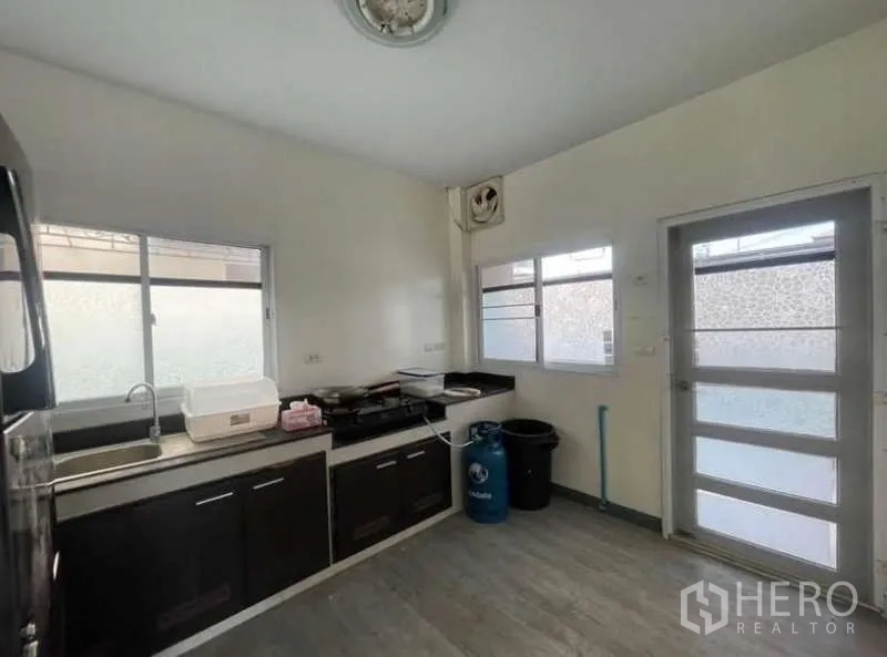 Detached House for rent in Bang Phli, Samut Prakan - Kitchen from another angle showing countertops, sink and gas cooktop.