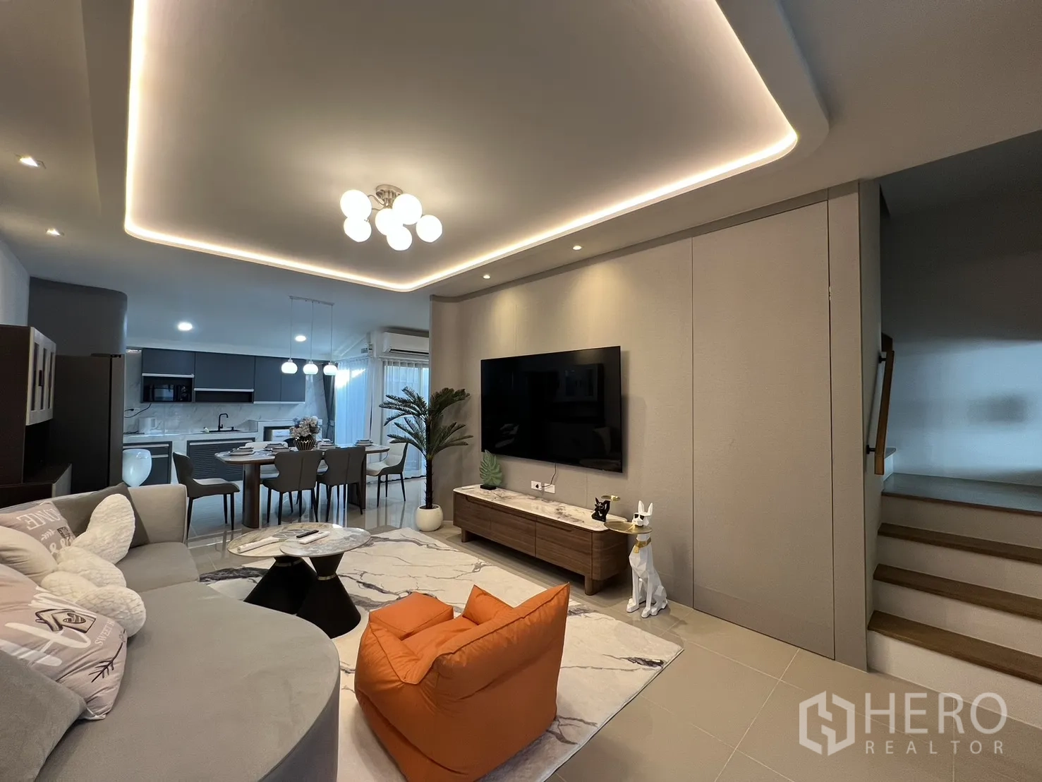 联排别墅 for rent in Bang Phli, Samut Prakan - 客厅设大屏电视墙、上楼楼梯与橙色懒人沙发。
