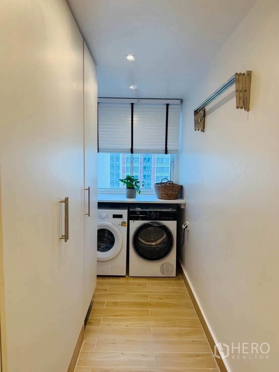 公寓 for rent or sale in Yan Nawa, Bangkok - 洗衣间，台下洗衣机和烘干机，收纳柜以及可见城市景观的窗户。