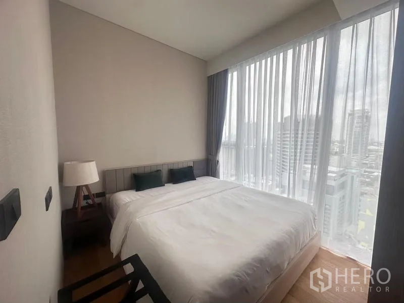 Condominium for rent - Second bedroom with double bed, bedside table and full-height windows overlooking the city.