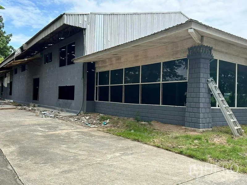 Warehouse for rent in Phra Nakhon Si Ayutthaya - Side view of warehouse under renovation with long window line and a ladder.