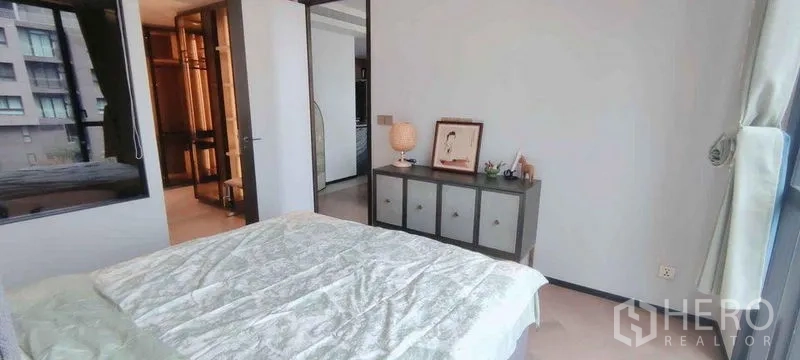 公寓 出租在Watthana, Bangkok - 卧室配中性色调、矮柜与通往更衣区的门。