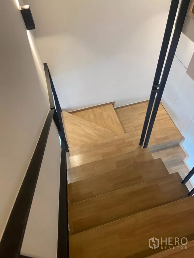 Townhouse for rent in Huai Khwang, Bangkok - Wood staircase with black metal railings viewed from above.