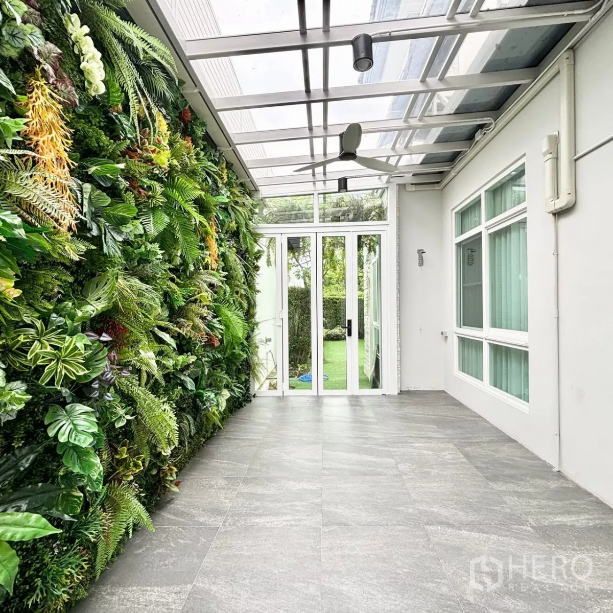 Detached House for rent or sale in Prawet, Bangkok - Covered terrace with glass roof and lush vertical garden leading to the backyard.
