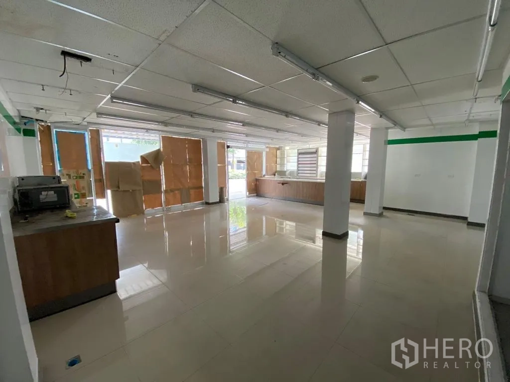 Retail Space for rent in Khlong Toei, Bangkok - Large front retail area with tiled floors and boarded street-facing windows.