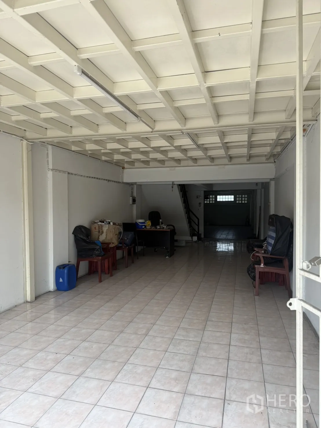 Shophouse for rent in Pak Kret, Nonthaburi - Ground-floor open shop space with roller shutter and seating.