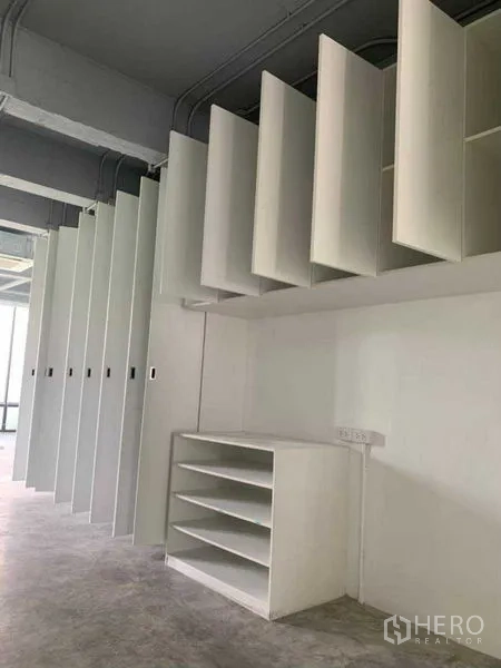 Office Space for rent in Khlong Toei, Bangkok - Modular white panel storage system and shelving beneath an exposed ceiling.