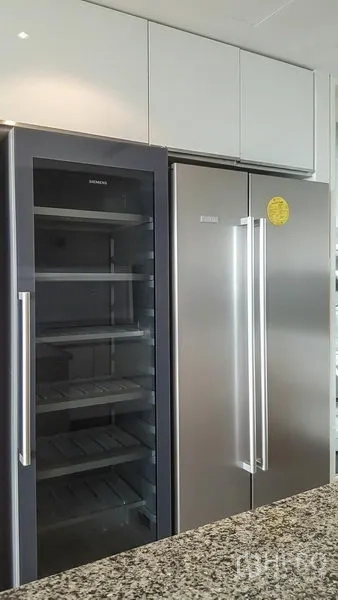 Condominium for rent or sale in Sathon, Bangkok - Kitchen with side-by-side refrigerator and glass-door wine cooler next to a granite countertop.