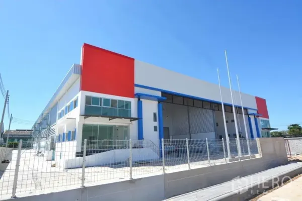 Factory for rent in Mueang Samut Prakan, Samut Prakan - Modern semi-detached factory exterior with glass-front offices, bold red accents, and fenced frontage at Bang Poo Industrial Estate.