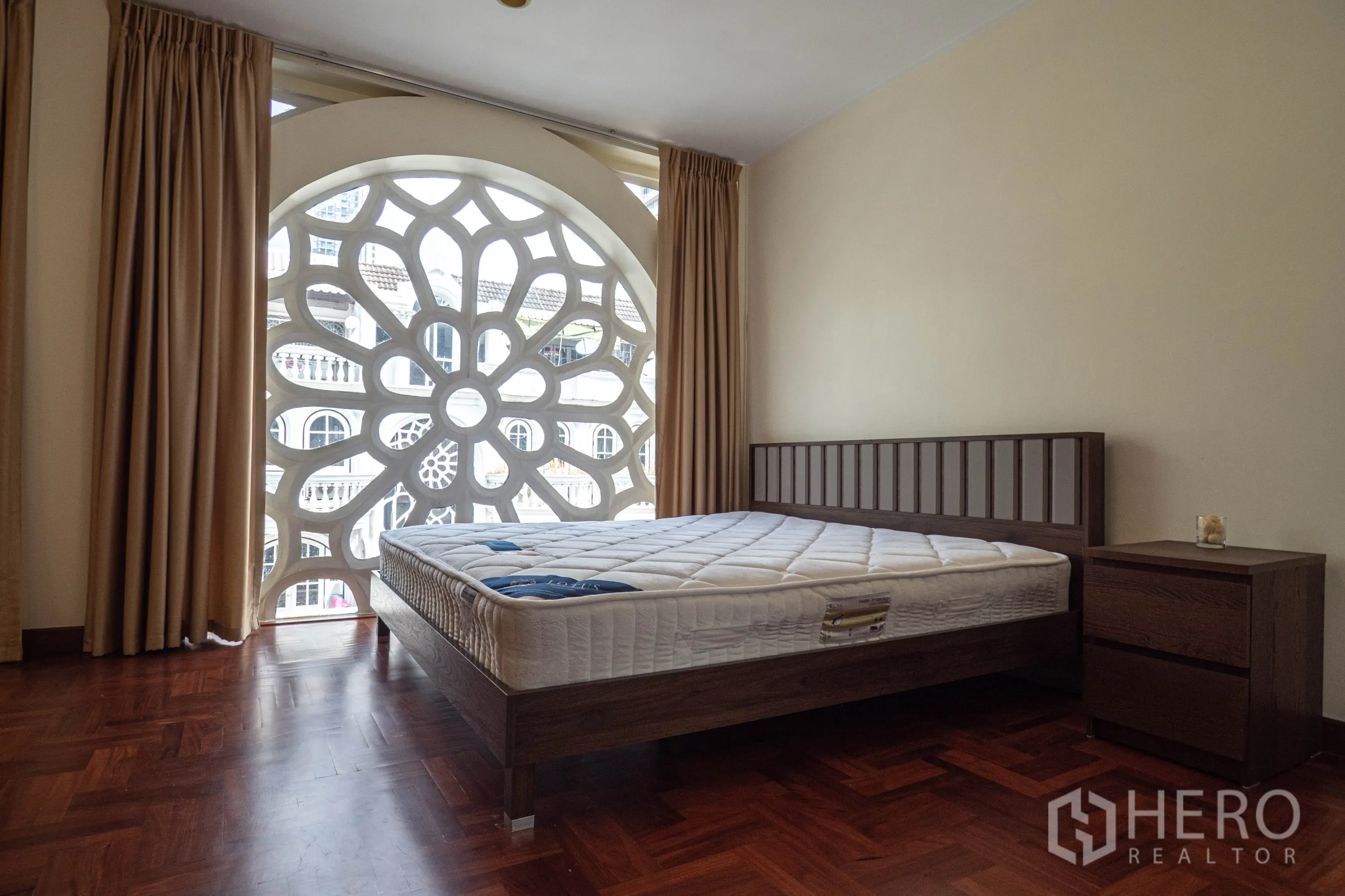 Townhouse for rent in Khlong Toei, Bangkok - Bedroom with wood floor, bed and a circular rosette-style window screen.