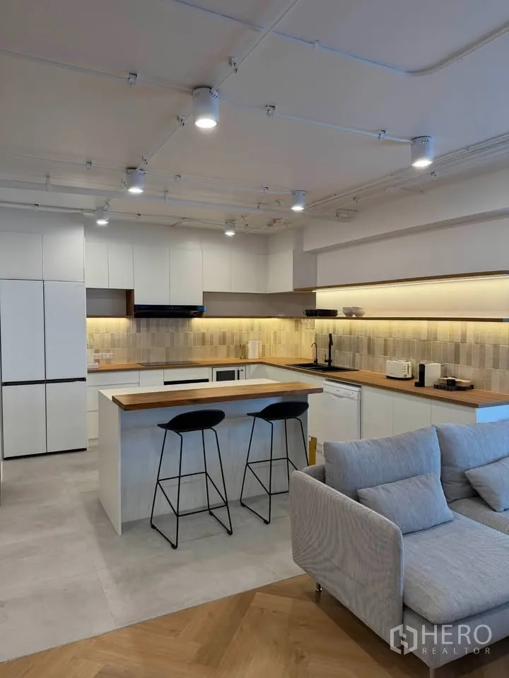 公寓 for rent in Watthana, Bangkok - 厨房带吧台与两张高脚凳，暖色灯光。
