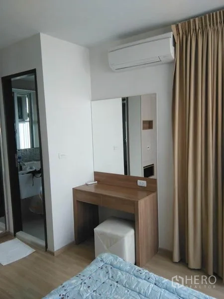 Condominium for rent in Sathon, Bangkok - Bedroom corner with dressing table, air conditioner and ensuite bathroom entrance.