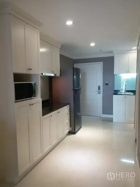 公寓 出租在Bang Rak, Bangkok - 独立厨房，白色橱柜、灶台、微波炉与大冰箱。