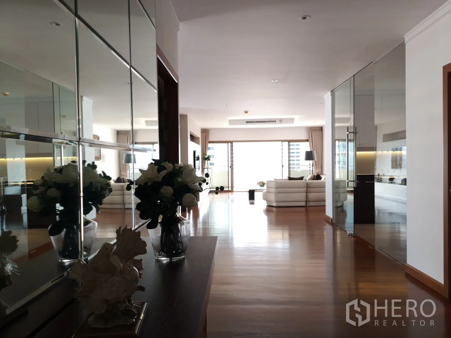 Condominium for rent in Bangkok - Mirror-lined hallway leading to bright lounge and balcony in a high-rise condo.